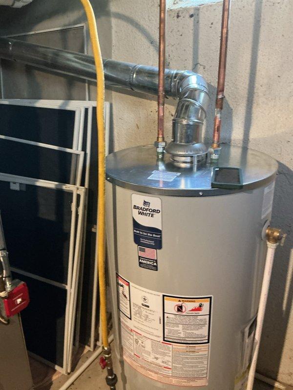 Completed installation and reconnection of a 50-gallon Bradford White tanked water heater in residential basement utility room. Connected copper supply lines, yellow flexible gas line, pressure relief valve, and all necessary piping to bring unit into full operation. All connections were properly secured and tested to ensure safe and efficient operation of the new water heating system.