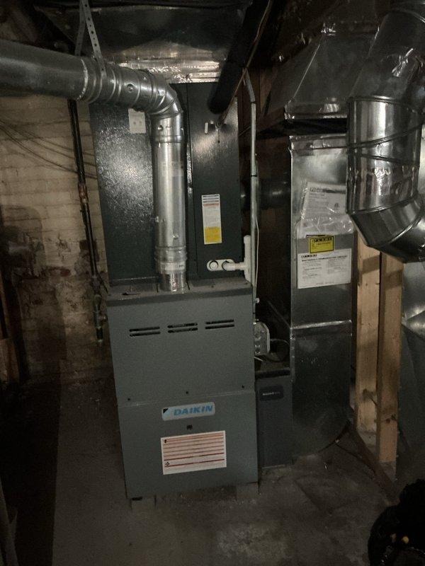 Completed comprehensive gold-level furnace inspection on a 4-year-old Daikin unit located in the basement. Performed full system evaluation including visual inspection of heat exchanger, burner assembly, and venting components. Verified proper ignition sequence and observed clean, even flame pattern across all four burners with appropriate blue flame characteristics indicating optimal combustion. Inspected blower motor operation, checked air filter condition, and examined all electrical connections for safety and proper function. Tested thermostat communication and confirmed system cycling properly. Documented equipment condition with photographs showing furnace installation, ductwork connections, and active burner operation. All components operating within manufacturer specifications with no immediate service needs identified.