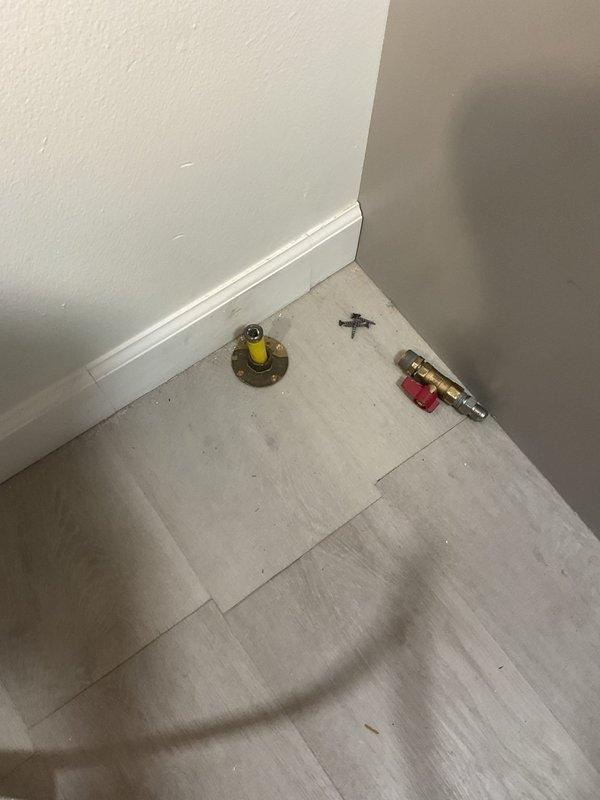 Responded to gas leak emergency where utility company had previously identified and disconnected a defective gas range connector at the stove location. Upon arrival, confirmed the gas line had been properly capped at the floor-level gas stub-out. Performed visual inspection of the disconnected flexible connector and verified the cap installation met code requirements. Inspected basement gas piping system to ensure no additional leaks were present in the distribution lines. Documented existing conditions with photographs showing the capped gas outlet with brass floor flange and yellow valve assembly, as well as the overhead gas distribution piping in the basement area. Advised on next steps for safe reconnection of gas appliance once approved replacement connector is obtained.