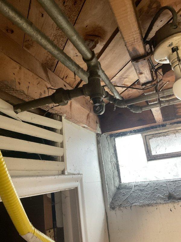 Responded to gas leak emergency where utility company had previously identified and disconnected a defective gas range connector at the stove location. Upon arrival, confirmed the gas line had been properly capped at the floor-level gas stub-out. Performed visual inspection of the disconnected flexible connector and verified the cap installation met code requirements. Inspected basement gas piping system to ensure no additional leaks were present in the distribution lines. Documented existing conditions with photographs showing the capped gas outlet with brass floor flange and yellow valve assembly, as well as the overhead gas distribution piping in the basement area. Advised on next steps for safe reconnection of gas appliance once approved replacement connector is obtained.