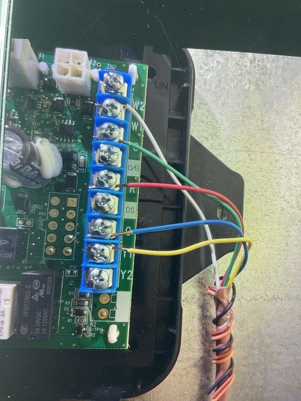 Responded to service call for thermostat malfunction causing air conditioning to activate when heating was called for, along with water leaking from exhaust PVC on less than one-year-old system. Inspected control board and thermostat wiring connections, documented existing wire terminations at both the air handler control board and thermostat interface. Found improper thermostat configuration causing incorrect system staging between heating and cooling modes. Verified all wire connections at terminal blocks were secure, checked capacitor and control board for signs of moisture damage or corrosion related to reported PVC leak. Photographed control board layout and wiring configuration for warranty documentation purposes. System remained operational throughout inspection. Advised that thermostat programming requires correction to resolve heating/cooling crossover issue, and PVC condensate drain requires further evaluation to identify source of water leak and prevent future moisture intru
