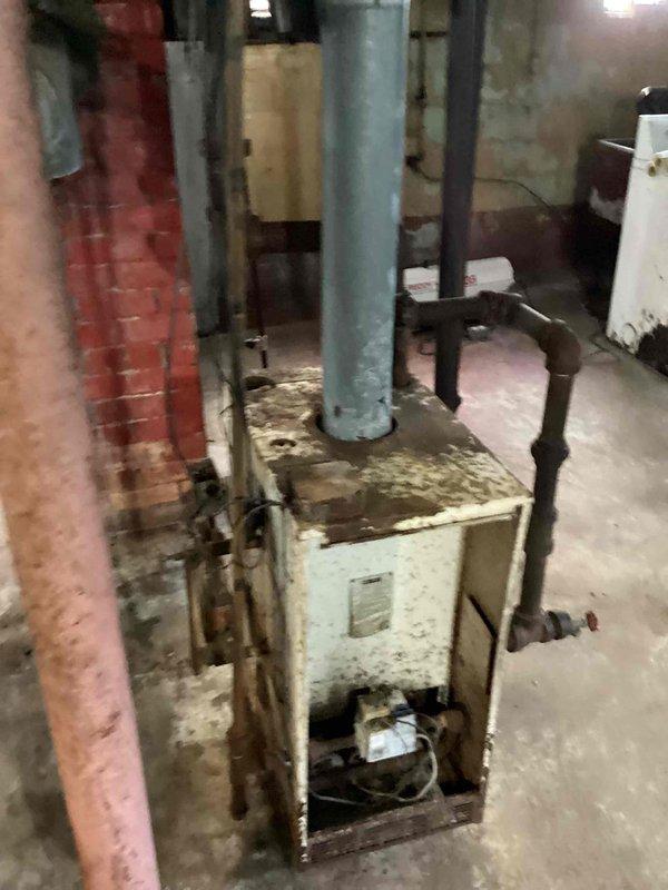 Provided estimate for complete steam boiler replacement due to flood damage and age-related deterioration of existing 10+ year old unit. Existing boiler system showed extensive corrosion, rust staining, and water damage throughout, rendering equipment beyond economical repair. Deteriorated chimney structure exhibited significant brick damage and structural compromise requiring attention during replacement process.