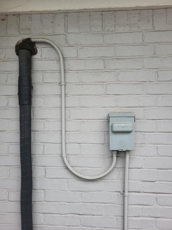 Evaluated existing 20-year-old Daikin mini split system with failed leaking coil requiring full system replacement. Assessed installation site for first-floor 3-season room application with outdoor condensing unit positioned on ground pad approximately 6 feet from indoor head location. Documented existing refrigerant line routing, electrical disconnect configuration, and exterior mounting conditions on white painted brick siding. Provided quote specifications for premium Daikin Atmosphera single-zone mini split system to replace failed equipment.