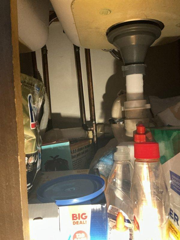 Responded to service call for multiple plumbing issues including kitchen sink leak, basement faucet replacement needs, and reduced shower pressure. Performed diagnostic inspection of kitchen sink plumbing system, identifying leak source at drain assembly and P-trap connections beneath double-basin stainless steel sink. Inspected under-sink plumbing configuration including PVC drain lines, compression fittings, and shut-off valves to assess leak points and determine necessary repairs for proper drainage function.