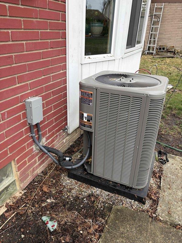Completed system start-up and inspection on recently installed HVAC system with outdoor condensing unit and basement air handler. Verified proper operation of all equipment components, checked refrigerant connections and electrical disconnect, and confirmed unit placement on appropriate pad with proper clearances. Documented installation with photographs showing plumbing connections at air handler and exterior condenser positioning against building foundation.