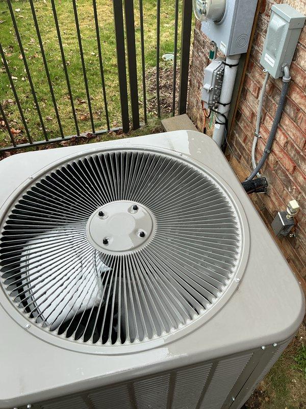 Completed comprehensive Gold AC Inspection and tune-up on a 2-year-old residential air conditioning system located on the north side of the property. Unit is positioned on a concrete pad against brick exterior wall with proper electrical disconnect and metering in place. Performed full preventive maintenance protocol including inspection of condensing unit, fan assembly, and all electrical connections. Verified proper operation of circular fan assembly with radial metal fins, checked refrigerant levels, cleaned condenser coils, and inspected louvered vents for adequate airflow. Examined electrical components including disconnect box and conduit connections mounted on building exterior. Unit operating within normal parameters with no deficiencies noted. System is in good condition for its age with proper installation on elevated pad for drainage. Membership renewal processed to include this maintenance visit.