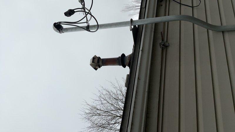 Completed installation of 40-gallon gas water heater at residential property. Installed new unit with proper venting through exterior wall, including red vent pipe with protective cap visible on building exterior. Connected gas supply line with required drip leg for condensation management and safety compliance. Verified all connections for proper operation and tested system functionality. Ensured venting meets code requirements for safe exhaust of combustion gases to building exterior.