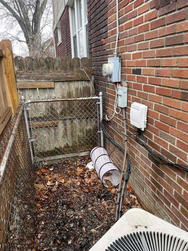 Conducted comprehensive site assessment for full HVAC system replacement at residential property. Evaluated existing gas furnace and outdoor condensing unit, both showing significant age and weathering. Documented current equipment configuration including exterior-mounted condenser unit on concrete pad in narrow side yard, electrical service connections via wall-mounted conduit and junction box, and utility access points. Photographed equipment placement, clearance constraints in confined side yard area between brick structure and chain-link fencing, and existing infrastructure for replacement planning. Assessed installation challenges including limited working space, proper clearances for new equipment, and electrical service requirements. Provided detailed estimate for complete system replacement including new high-efficiency gas furnace and matching outdoor condensing unit.
