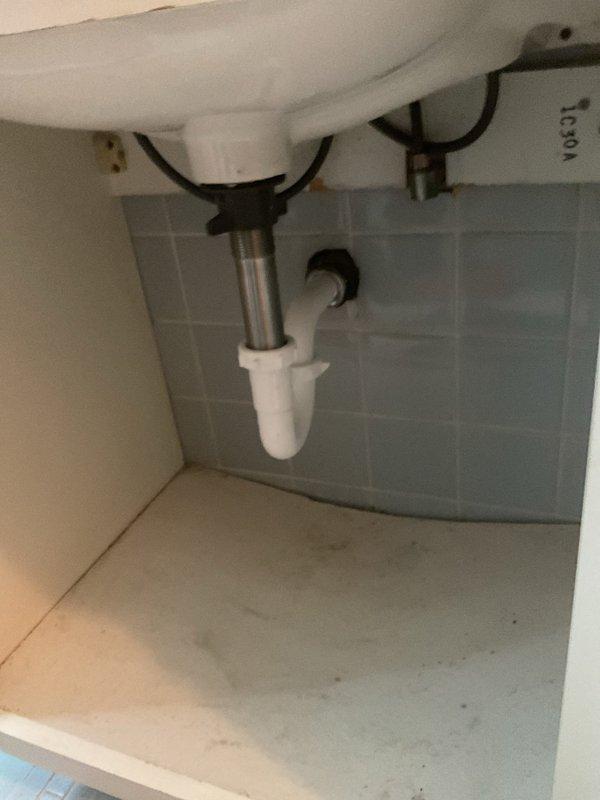Responded to a plumbing service call for bathroom sink maintenance. Upon inspection, serviced a traditional two-handle chrome faucet and white porcelain sink assembly. Verified proper operation of the drain stopper mechanism and inspected the P-trap assembly beneath the sink, confirming all PVC drain connections and chrome tailpiece were secure and leak-free. Checked both hot and cold water supply lines with mounting brackets for proper connection to the faucet assembly. All plumbing components were found to be in standard working condition with no visible leaks or damage detected.