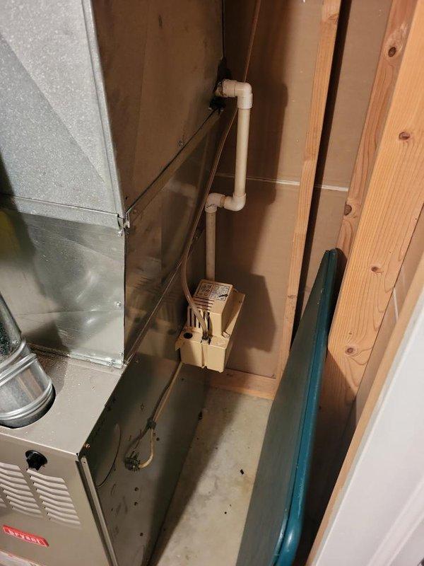 Provided comprehensive estimate for replacement of 38-year-old air conditioning system currently located in basement alongside existing natural gas furnace and associated ductwork. Assessed current equipment configuration, including metal air handler unit with silver metallic finish, existing PVC condensate drainage system with pump, and evaluated basement space conditions for new equipment installation. Documented equipment specifications and site conditions to develop replacement options for aging but currently operational AC system.