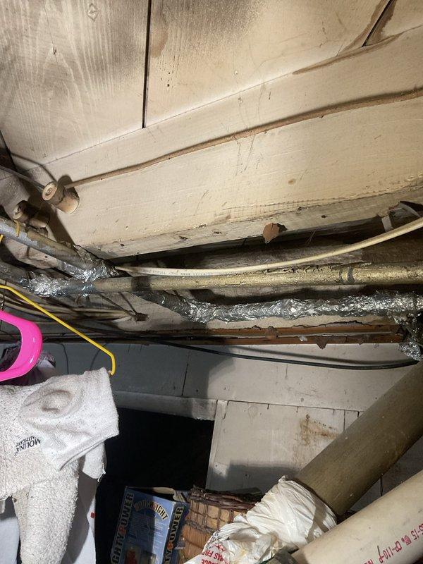 Responded to service call for leaking kitchen faucet that would not shut off completely. Upon inspection, found wall-mounted chrome faucet assembly with dual handles on cast iron sink basin showing signs of age and mineral buildup. Accessed plumbing connections from crawl space beneath sink to diagnose issue. Repaired faulty valve mechanism preventing complete water shutoff, restoring proper function to faucet handles and eliminating leak.