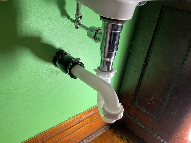 Responded to a chronic drainage issue in a third-floor bathroom that had persisted for approximately six months. Upon inspection, found a vintage wall-mounted ceramic sink with significant staining and buildup in the basin, indicating long-term slow drainage problems. Examined the drain assembly and P-trap configuration beneath the sink, which consisted of chrome tailpiece connected to white plastic P-trap with rubber coupling and metal clamps. Assessed the condition of all plumbing connections, drain lines, and trap assembly for blockages, improper venting, or deterioration. The aging fixture showed considerable wear and staining consistent with extended use and potential mineral deposit accumulation. Documented existing conditions of the vintage sink, drain assembly, supply connections, and overall plumbing configuration. Due to the age and condition of the fixture, recommended consideration for sink replacement as a long-term solution to prevent recurring drainage issues and improve