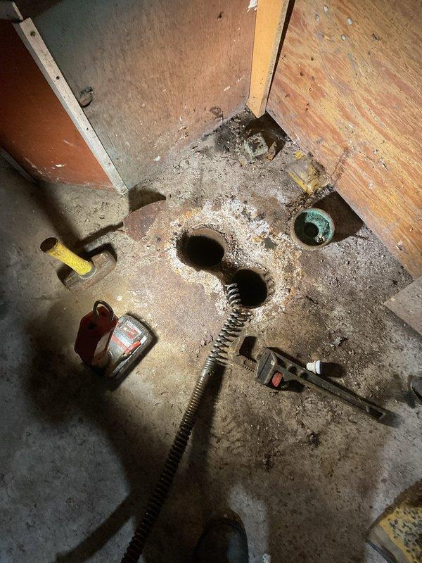 Responded to basement drain backup occurring in specific area following laundry use. Upon arrival, found standing water covering basement floor with visible moisture damage on walls indicating active flooding condition. Performed main drain cleanout service by accessing floor drain openings and utilizing mechanical augering equipment to clear blockage in main sewer line. Successfully removed obstruction and restored proper drainage flow, eliminating backup issue. Tested system to verify complete clearance and proper function of drainage system.