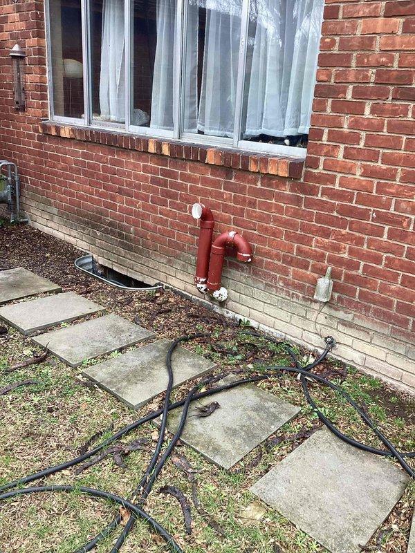 Provided estimate for replacement of 14-year-old natural gas furnace located in basement that sustained flood damage and ceased operation. Assessed existing gray metallic furnace unit within wooden frame structure, noting flood-related failure and need for complete system replacement. Documented current installation including ductwork connections, exhaust/intake piping, and exterior gas line configuration with shut-off valves mounted to brick foundation.