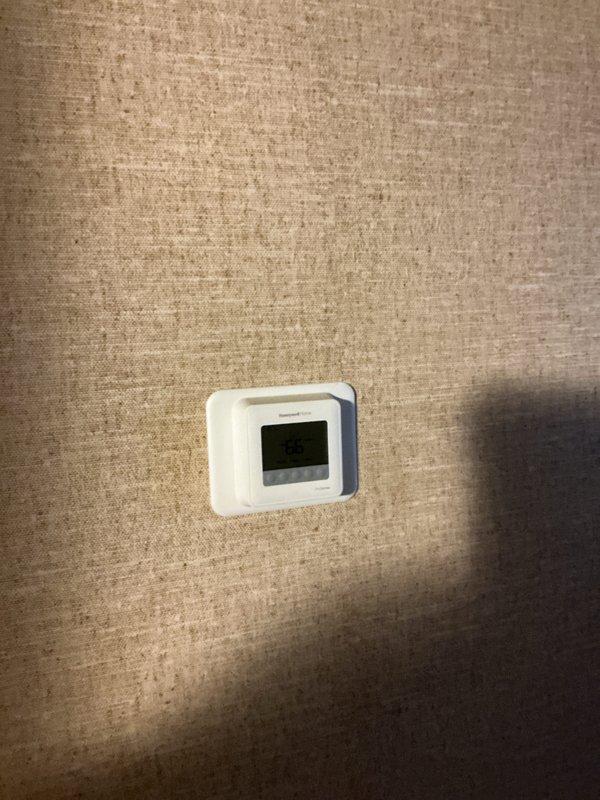 Conducted on-site evaluation of a non-operational high-pressure HVAC system exceeding 25 years of service life with components located in the attic and exterior of the property. Assessed existing five-ton air conditioning system configuration, including outdoor condensing unit with cylindrical design and indoor air handling equipment. Documented current system conditions through photographic inspection, noting thermostat location and exterior unit placement along building siding with adjacent electrical conduit routing. Provided comprehensive replacement options and sizing recommendations for new HVAC system installation, discussing equipment specifications suitable for the existing ductwork infrastructure and space requirements.