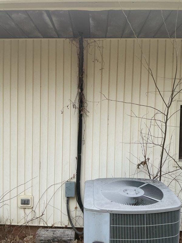 Conducted on-site evaluation of a non-operational high-pressure HVAC system exceeding 25 years of service life with components located in the attic and exterior of the property. Assessed existing five-ton air conditioning system configuration, including outdoor condensing unit with cylindrical design and indoor air handling equipment. Documented current system conditions through photographic inspection, noting thermostat location and exterior unit placement along building siding with adjacent electrical conduit routing. Provided comprehensive replacement options and sizing recommendations for new HVAC system installation, discussing equipment specifications suitable for the existing ductwork infrastructure and space requirements.