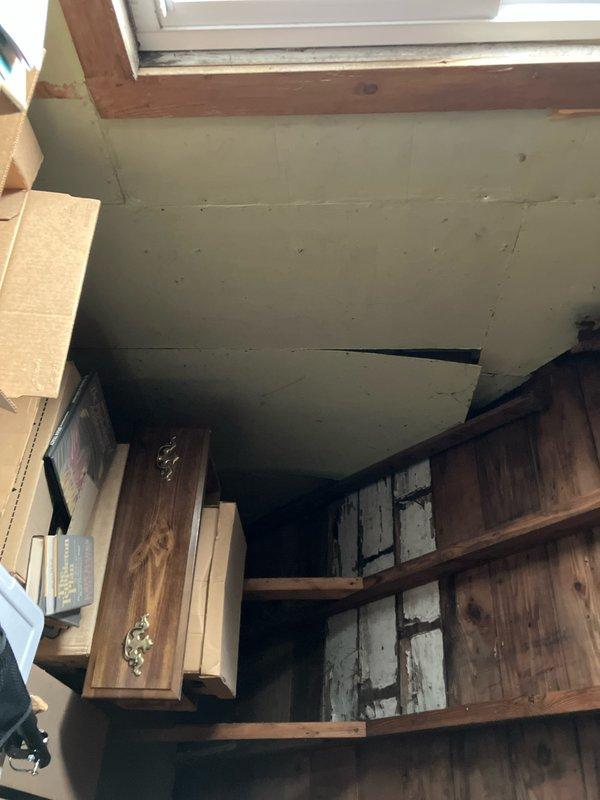 Conducted on-site evaluation for new mini split installation in attic space. Assessed structural conditions including skylight area, built-in shelving, and window locations to determine optimal placement for indoor air handler and refrigerant line routing. Documented existing fire damage to wooden framing and joists surrounding window area, noting charred structural members that may require remediation or reinforcement prior to installation to ensure proper mounting and system support.
