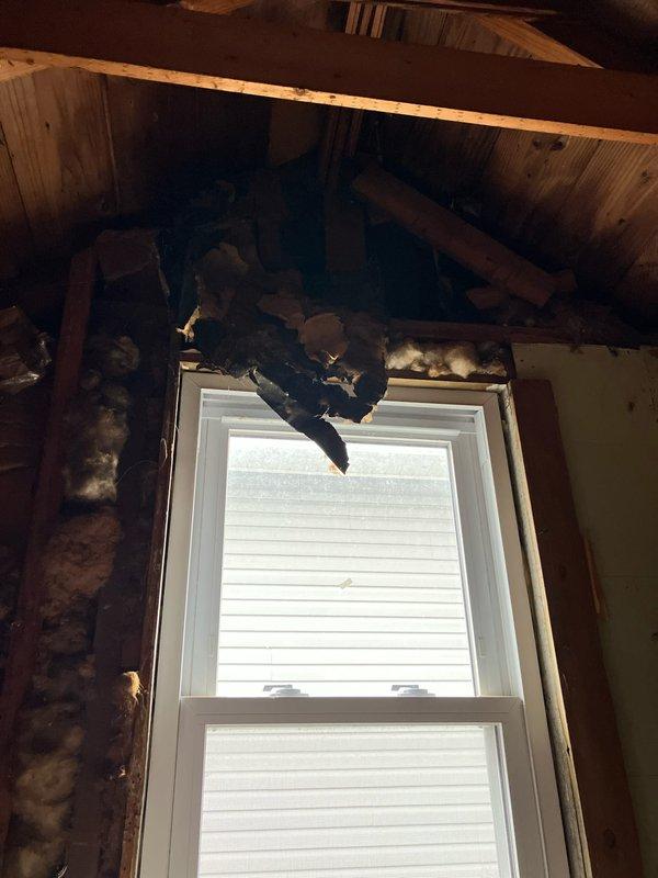 Conducted on-site evaluation for new mini split installation in attic space. Assessed structural conditions including skylight area, built-in shelving, and window locations to determine optimal placement for indoor air handler and refrigerant line routing. Documented existing fire damage to wooden framing and joists surrounding window area, noting charred structural members that may require remediation or reinforcement prior to installation to ensure proper mounting and system support.