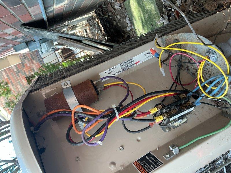 Completed comprehensive Gold AC inspection on 10+ year old residential air conditioning system with air handler located in basement. Performed full system evaluation including outdoor condenser unit examination, electrical component inspection, and refrigerant line assessment. Inspected condenser pad showing signs of age with weathering, algae growth, and concrete cracking; noted accumulation of fallen leaves and debris around unit perimeter. Examined internal electrical components, capacitor, wiring connections, and control panel for proper operation and safety. Documented system condition through photographic inspection of both exterior condenser unit and interior electrical components. Unit confirmed operational at time of inspection with all components functioning within normal parameters for equipment age.