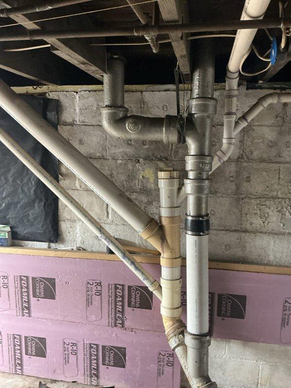 Responded to service call for leaking downstairs wastewater pipe in basement area. Upon inspection, identified compromised PVC drainage piping running along concrete block foundation wall. Assessed plumbing system configuration including vertical and horizontal drain lines with multiple joints and fittings. Evaluated pipe connections and determined source of water leak in wastewater drainage system. Completed necessary repairs to eliminate active leak and restore proper drainage function. Verified system integrity and confirmed no additional moisture intrusion following repair completion.