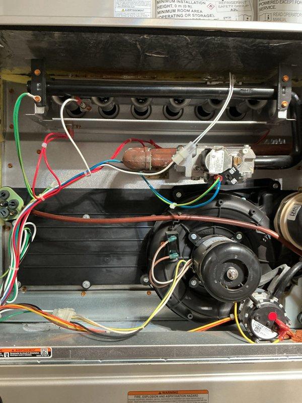 Completed comprehensive Gold-level inspection on residential HVAC system consisting of 10+ year old furnace and air conditioning unit. Performed thorough multi-point evaluation of furnace located in basement, inspecting burner assembly, heat exchanger, gas valve operation, blower motor assembly, and all electrical connections. Examined outdoor condensing unit, verifying fan motor operation, condenser coil condition, and proper airflow through top-mounted fan guard. Confirmed both heating and cooling systems operational at time of inspection. Documented equipment condition through photographic records showing internal furnace components including burner assembly, flame sensor, ignition system, and blower motor, as well as exterior condenser unit with protective fan grille. Verified area surrounding outdoor unit maintained clear of debris for optimal performance.