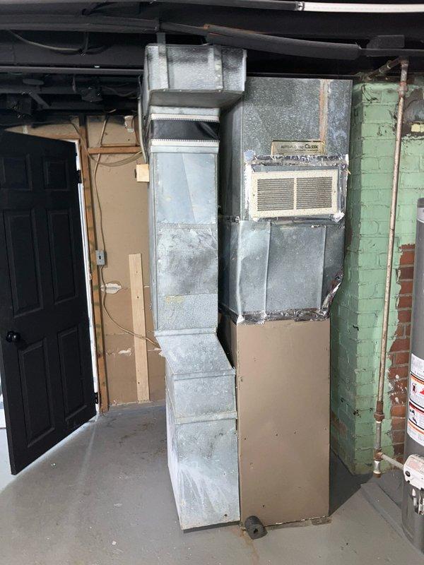 Conducted on-site assessment of non-operational natural gas furnace located in basement. Evaluated existing 10+ year old heating system showing significant age-related deterioration, dust accumulation, and general wear. Documented current equipment configuration including furnace unit, thermostat, and ductwork to provide comprehensive replacement estimate for new gas-fired heating system.
