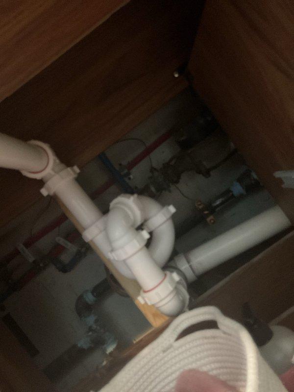 Responded to persistent sewage odor in bathroom of 1947-built home that began following previous drywall opening for leak repair behind toilet and washer/dryer area. Investigated exposed wall cavity revealing brick masonry construction with existing plumbing infrastructure including PVC drain/vent lines with visible purple primer at joints, flexible supply lines with brass fittings, and under-sink P-trap configuration with adjacent water filtration system. Inspected all visible plumbing connections, drain lines, and vent stack penetrations within the opened wall section to identify potential sewer gas escape points. Evaluated PVC joint integrity, trap seal functionality, and proper venting to determine source of eight-month odor issue confined to bathroom space.