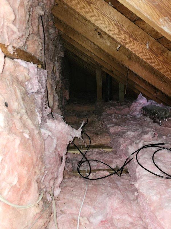 Conducted comprehensive site assessment for high velocity air conditioning system installation. Evaluated attic space for equipment placement and ductwork routing, noting existing insulation conditions with pink and yellow fiberglass materials present throughout space. Documented structural elements including exposed wooden rafters, joists, and framing to determine optimal system configuration. Photographed attic access points, available clearances, and existing electrical wiring for system planning purposes. Assessment completed to provide accurate estimate for full high velocity AC system installation.