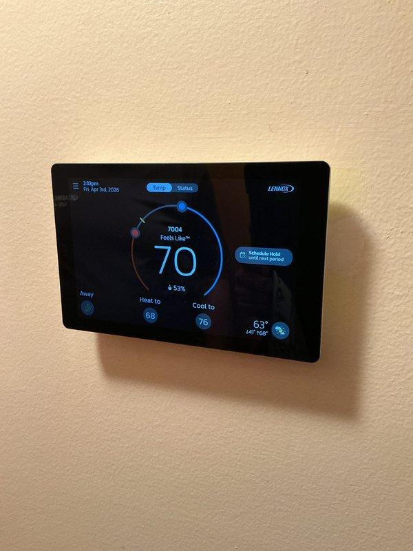Completed system start-up and commissioning of newly installed Lennox air conditioning system. Verified outdoor condenser unit is properly positioned on pad with adequate clearance, confirmed all electrical connections are secure and properly terminated at junction boxes, and tested condensate drain line for proper operation. Programmed and configured Lennox digital thermostat, verified system communication between indoor and outdoor units, and confirmed heating and cooling setpoints are functioning correctly with proper temperature readings and humidity display at 53%.
