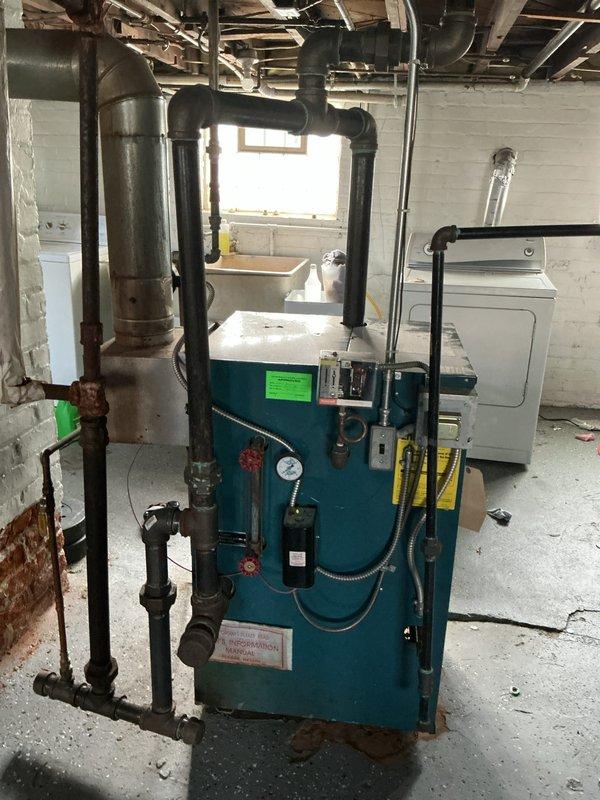 Responded to service call for steam boiler system experiencing pilot light failure and flashing programmable feeder indicator. Performed diagnostic inspection of basement-located steam boiler unit and discovered cracked heat exchanger. Observed extensive corrosion and deterioration on supply piping throughout system. Documented equipment condition with photographic evidence showing compromised heat exchanger, corroded vertical piping, and overall system age. Provided comprehensive estimate for steam boiler replacement due to failed heat exchanger and safety concerns.