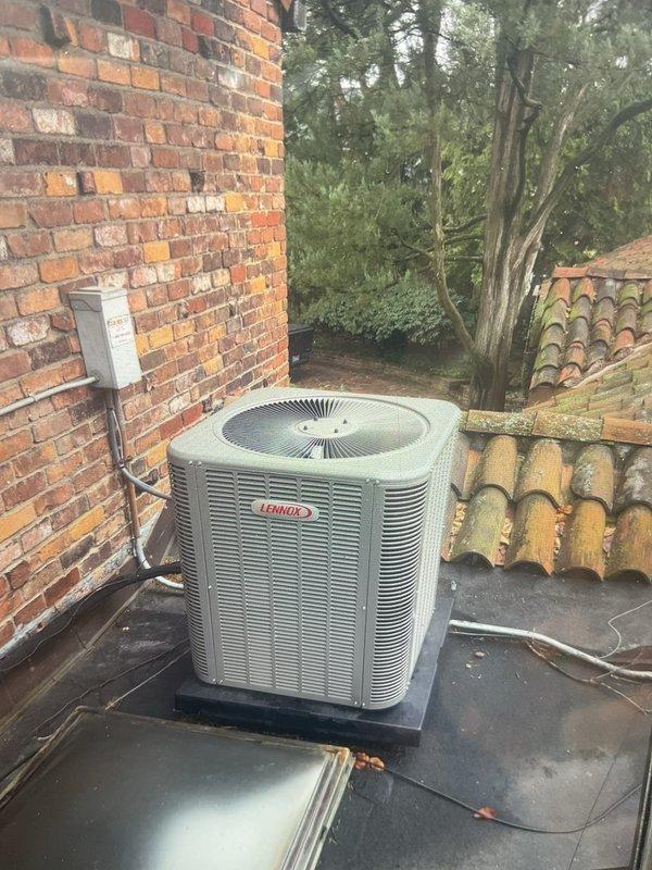 Completed routine Gold AC maintenance inspection on 2-year-old Lennox air conditioning condenser unit located on elevated rooftop overhang. Performed comprehensive system tune-up including visual inspection of outdoor unit, verified proper electrical connections at disconnect box, checked refrigerant levels, cleaned condenser coils, inspected fan operation, and confirmed overall system performance. Unit operating within normal parameters with no deficiencies noted.