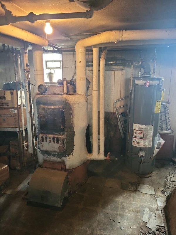 Provided estimate for boiler replacement in basement mechanical room. Existing unit is operational but shows extensive rust, corrosion, and deterioration throughout metal casing and combustion chamber area, indicating advanced age and end of service life. Documented current equipment condition and discussed replacement options with customer.