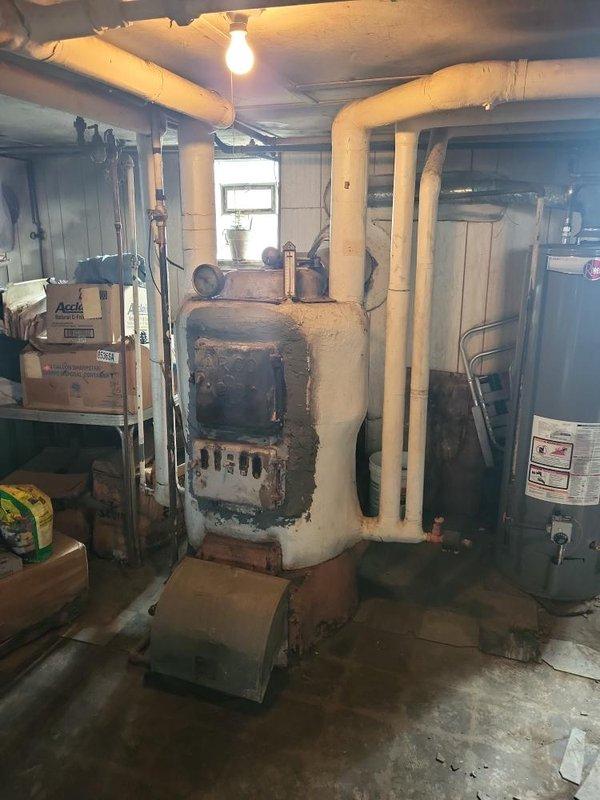 Provided estimate for boiler replacement in basement mechanical room. Existing unit is operational but shows extensive rust, corrosion, and deterioration throughout metal casing and combustion chamber area, indicating advanced age and end of service life. Documented current equipment condition and discussed replacement options with customer.