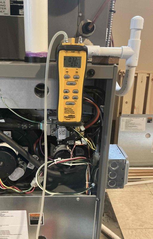 Responded to service call for banging sounds in vents and rattling noise from recently installed furnace. Performed diagnostic testing using dual port manometer to measure static pressure readings throughout the system, recording measurements at supply and return plenums. Readings indicated potential airflow imbalance with supply pressure at 0.32" and return at -0.30". Inspected internal furnace components including blower motor assembly, wiring connections, and condensate drainage system. Verified all electrical connections were secure and properly terminated. Checked blower motor mounting and housing for loose hardware that could cause rattling. Examined ductwork connections at plenum for proper sealing and secure fastening to eliminate banging sounds. System remained operational throughout diagnostic process with heating capability confirmed.