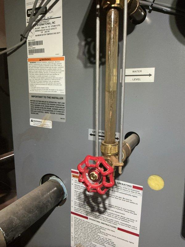 Responded to service call for boiler experiencing persistent low water level issues despite having an operational automatic feeder. Upon arrival, verified heating system remained functional. Conducted thorough inspection of boiler water level controls, feed system components, and associated valves. Examined red gate valve on brass piping, water level indicators, and automatic feeder mechanism for proper operation. Documented current system conditions with photographic evidence showing thermostat operation and boiler equipment configuration. Identified potential issues with automatic water feeder requiring further monitoring or component replacement to maintain proper water levels and prevent future system complications.