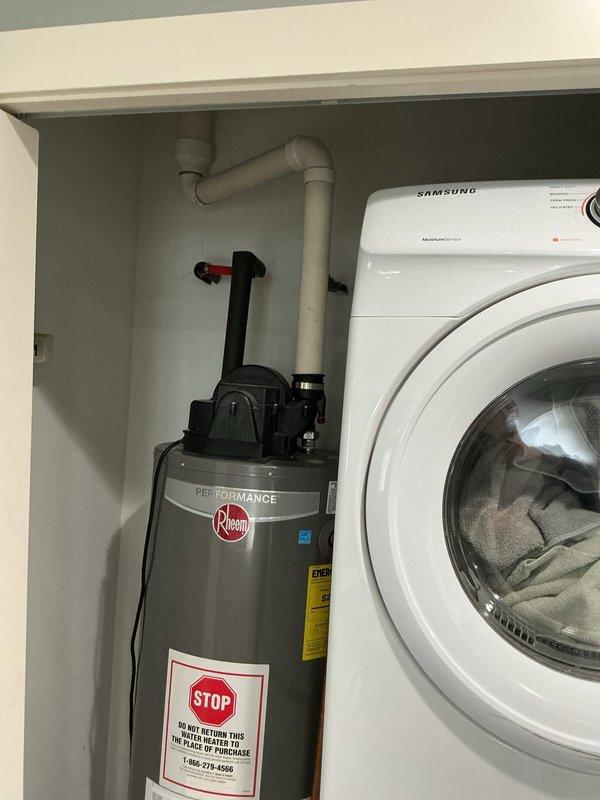 Responded to service call for Rheem Performance gas water heater with pilot light extinguishing on a recurring three-week cycle. Performed diagnostic inspection of the unit located in utility closet adjacent to laundry appliances. Examined thermocouple, gas control valve, pilot assembly, and venting system to identify cause of intermittent pilot failure. Documented equipment condition and configuration with photographic evidence for service records.