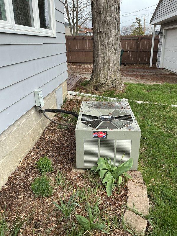 Provided estimate for replacement of non-operational 30-year-old Rheem outdoor air conditioning unit and natural gas furnace system. Unit showed significant deterioration including rust, discoloration, and compromised protective coating on exterior cabinet. Assessed existing installation including refrigerant line penetration through foundation, concrete pad condition, and clearance requirements around equipment positioned in landscaped area near home exterior.