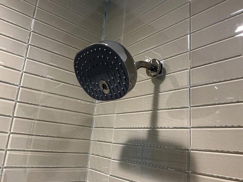 Completed installation of new bathroom shower and tub fixtures including a matte black circular rainfall shower head with chrome adjustable ball-joint arm and matching tub spout with chrome trim control valve. All fixtures were properly mounted to subway-tiled walls, connections tested for proper water flow and pressure, and system verified leak-free upon completion.