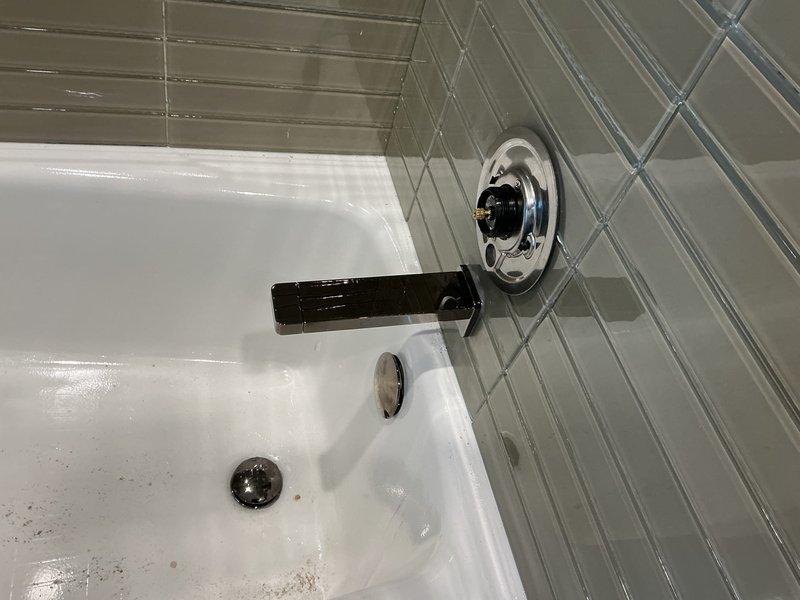 Completed installation of new bathroom shower and tub fixtures including a matte black circular rainfall shower head with chrome adjustable ball-joint arm and matching tub spout with chrome trim control valve. All fixtures were properly mounted to subway-tiled walls, connections tested for proper water flow and pressure, and system verified leak-free upon completion.