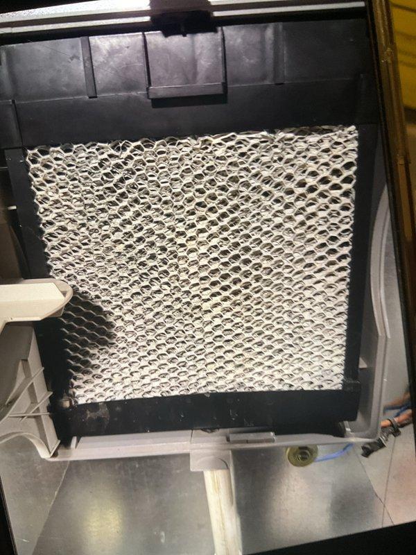 # AC Tune-Up Completed

Performed comprehensive annual maintenance inspection on 5-year-old air conditioning system located in backyard as part of prepaid maintenance membership. Conducted complete system evaluation including refrigerant level check, electrical component testing, and condenser coil inspection. Verified proper operation of compressor and fan motor. Inspected and documented humidifier filter pad condition, noting honeycomb mesh pattern intact with minimal debris accumulation. Examined plumbing connections associated with humidifier system, including copper piping and brass shut-off valve with proper accessibility. All components found operating within manufacturer specifications. System performing efficiently with no immediate service needs identified. Unit cleared for continued operation through next scheduled maintenance interval in 2026.