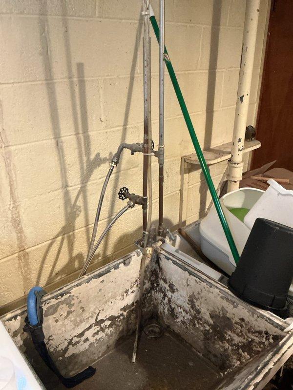 # Plumbing Service - Clogged Drain/Sink

Responded to a main drain backup issue affecting the kitchen drainage system. Upon arrival, found the main drain line was experiencing blockage causing water to back up when kitchen fixtures were in use, while bathroom drains remained functional. Inspection revealed significant water damage on the basement floor with standing water and staining patterns indicating recent overflow events.

Located the main drain cleanout access point in the basement utility area near the plumbing assembly. Assessed the drainage system configuration including vertical stack pipes and horizontal drain lines. Utilized drain cleaning equipment to clear the obstruction in the main line. Successfully restored proper drainage flow to the kitchen plumbing system. Verified clearance by running water through kitchen fixtures and confirming no backup occurred. Advised on the existing water damage conditions observed in the basement and recommended monitoring for future drai