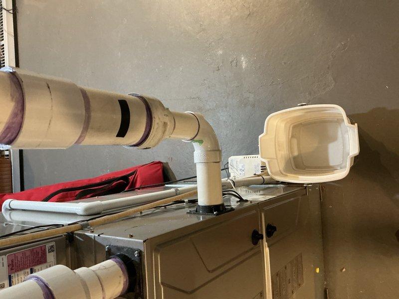 Responded to callback for water dripping from furnace following recent maintenance visit. Upon inspection, identified active condensate leak from furnace drain line and associated PVC piping connections in basement. Condensate drain pan was positioned beneath leak to collect water. Inspected all drain line connections, fittings, and trap assembly for proper sealing and alignment. Addressed leak source by resealing affected connection points and verified proper pitch on condensate drain line to ensure adequate drainage. Tested system operation to confirm condensate was flowing correctly through drain system without further leakage. Verified furnace operation and monitored for several cycles to ensure issue was fully resolved.