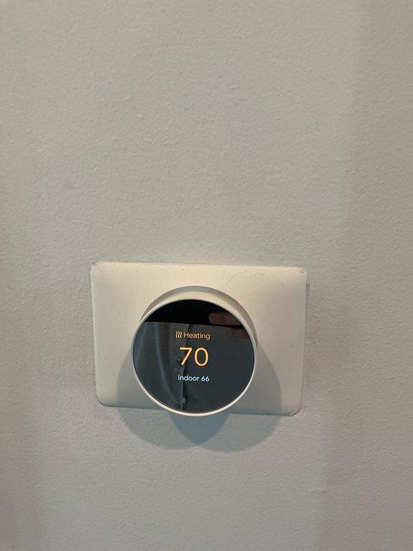 Responded to service call for heating issue affecting only half of the residence after homeowner self-installed a new Nest thermostat in hallway location. Performed diagnostic evaluation of the newly installed thermostat system, which displayed heating mode active at 70°F setpoint with indoor temperature reading 66°F. Verified proper thermostat mounting, wiring connections, and system communication to identify cause of partial heating distribution issue and restored full system functionality.