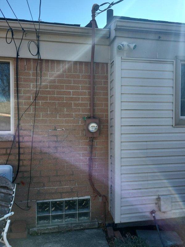 Conducted comprehensive site evaluation for full HVAC system replacement at residential property with significantly aged equipment. Existing outdoor condenser unit exhibited severe deterioration with extensive vegetation overgrowth, debris accumulation, and compromised airflow around unit perimeter. Equipment showed visible weathering, discoloration, and structural wear consistent with end-of-service-life conditions. Documented current system configuration including exterior condenser placement adjacent to building foundation with glass block basement windows and mixed brick-vinyl siding construction. Assessed clearance requirements and noted substantial vegetation management needed for proper equipment operation and future accessibility. Photographed existing installation conditions to support full system replacement estimate and equipment specifications.