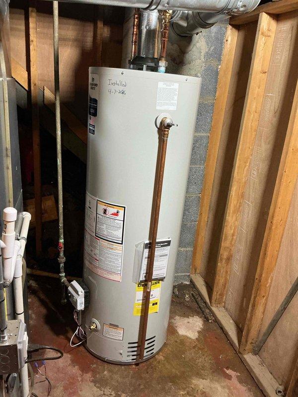 Successfully reconnected a 40-gallon standard gas water heater in the basement utility area. The unit was properly positioned against the concrete block wall with copper supply lines connected to the top of the tank, pressure relief valve installed with discharge pipe, and all plumbing connections secured. The installation includes proper venting with flexible ductwork routed through the ceiling joists, ensuring safe exhaust of combustion gases. All manufacturer labels, safety warnings, and energy guide information remain visible and intact on the unit for future reference and compliance purposes.