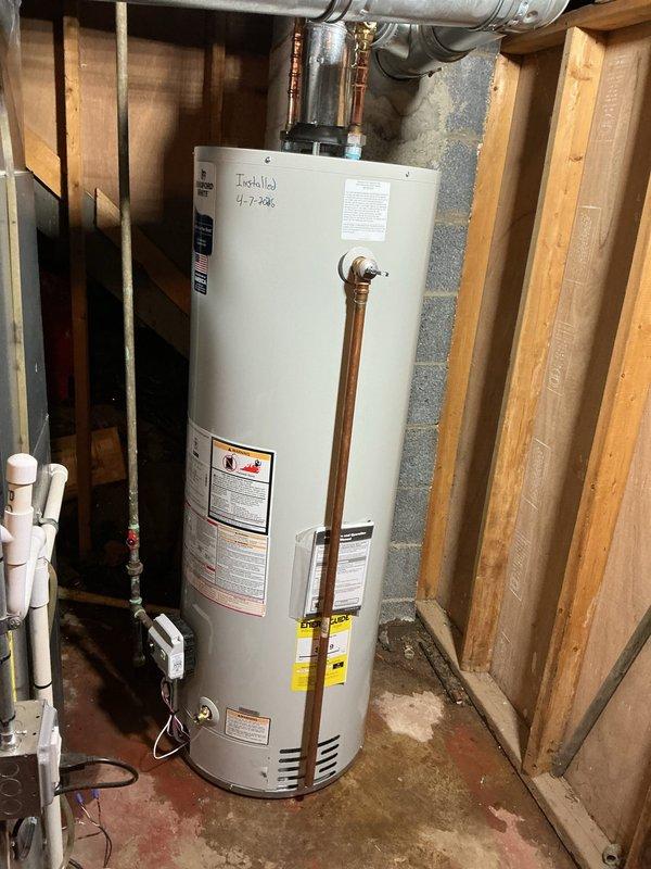 Successfully reconnected a 40-gallon standard gas water heater in the basement utility area. The unit was properly positioned against the concrete block wall with copper supply lines connected to the top of the tank, pressure relief valve installed with discharge pipe, and all plumbing connections secured. The installation includes proper venting with flexible ductwork routed through the ceiling joists, ensuring safe exhaust of combustion gases. All manufacturer labels, safety warnings, and energy guide information remain visible and intact on the unit for future reference and compliance purposes.