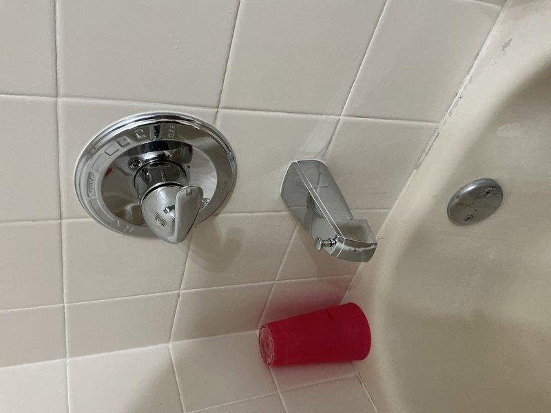 Responded to reported leaking shower valve and unidentified water drip beneath bathroom sink, both issues present for approximately two weeks. Accessed plumbing components through closet access panel to diagnose and address leak source. Repaired faulty shower valve assembly and identified source of drip under sink, resolving both water intrusion concerns. Documented conditions with photos showing access point and shower fixture area for service records.