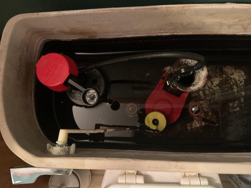Responded to service call for water heater producing whistling noise and slow-filling toilet tank. Inspected toilet tank and identified significant mineral deposits and hard water buildup throughout interior surfaces, affecting fill valve performance. Fill valve assembly showed signs of age with corroded components and sediment accumulation restricting water flow, causing extended fill times. Flapper valve exhibited mineral buildup and weathering. Examined water heater and diagnosed whistling noise originating from sediment accumulation in tank causing steam pockets during heating cycle. Documented condition of both fixtures with photographs showing extent of mineral deposits and component degradation. Provided recommendations for fill valve replacement, flapper replacement, and water heater tank flushing to restore proper operation and eliminate noise issues.