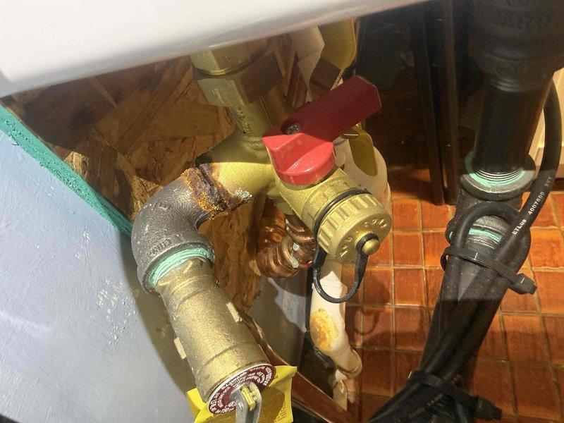 Responded to water leak concern at tankless water heater installation. Upon inspection, discovered significant rust and corrosion around pipe connections, fittings, and brass components at the pressure relief valve assembly. The unit, approximately one year old, showed premature deterioration at threaded connections and elbow joints. Documented corrosion patterns on copper and brass fittings, particularly around the pressure relief valve with red handle and associated piping. Photographed affected areas showing oxidation on metallic surfaces and compromised pipe joints that could lead to future leak points if left unaddressed.