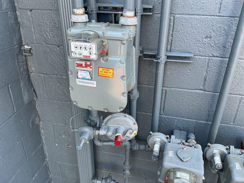 Responded to commercial property for evaluation of inadequate gas line pressure affecting building operations. Upon inspection, assessed the existing natural gas meter installation, pressure regulator assembly, and distribution piping system mounted on exterior wall. Evaluated gas supply capacity and pressure delivery to connected appliances, including water heating equipment. Documented current gas meter configuration, shut-off valve locations, pressure regulation components, and piping infrastructure to determine system deficiencies and develop recommendations for upgrading gas line capacity to meet facility demand requirements.